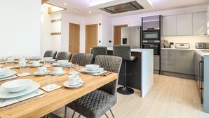 Un comedor moderno con una mesa de madera dispuesta para una comida, rodeada de sillas acolchadas.