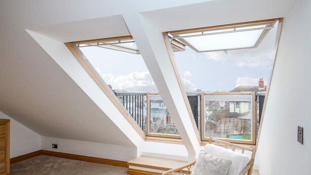 A room with a sloped ceiling, skylights, a bed, and a view of the outside. - Family House (Weymouth)