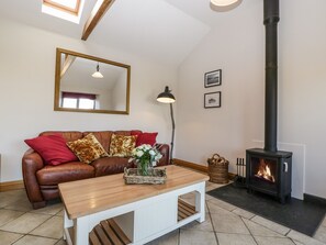 A cozy living room with a brown leather sofa, a wooden coffee table, a fireplace, and a large mirror on the wall.