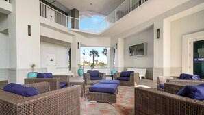 A spacious lobby with wicker furniture and a view of palm trees.