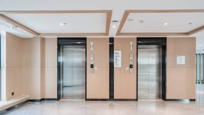 A modern elevator area with two elevators, wooden paneling, and a marble floor. - Holiday Inn Express Linzhi Airport by IHG (Nyingtri)