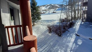 Eine hölzerne Veranda mit Blick auf eine verschneite Landschaft und einen Skiort im Hintergrund.