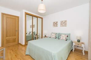 Ein Schlafzimmer mit einem großen Bett, einem Holzschrank, einem Spiegel und zwei an der Wand befestigten Bilderrahmen.