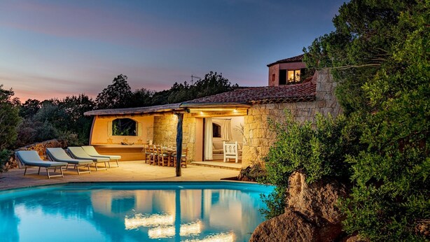 A poolside villa with a stone exterior, a dining area, and a pool. - Casa Chenal 10 Emma Villas (Arzachena)