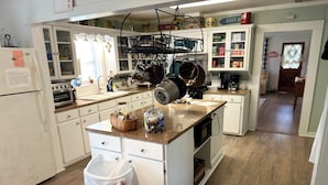 A kitchen with white cabinets, a granite countertop, a stainless steel range hood, and a trash can. - Country Farm House (Oberlin)