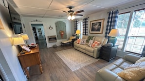 A living room with a beige sofa, a wooden coffee table, a lamp, and a ceiling fan. - Country Farm House (Oberlin)