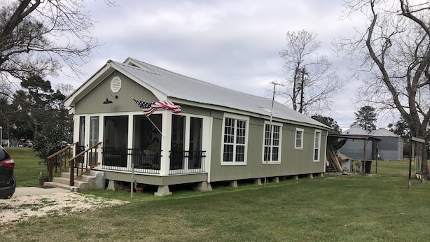 A single-story house with a porch, a small staircase, and an American flag. - Country Farm House (Oberlin)