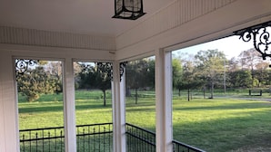 A covered porch with a view of a grassy park area. - Country Farm House (Oberlin)