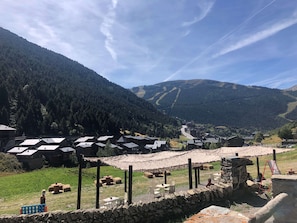 Un village rural aux bâtiments en pierre, doté d’un mur de pierre et offrant une vue dégagée sur les montagnes environnantes.