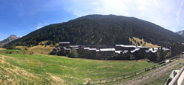 A mountain lodge with multiple chalet-style buildings, surrounded by forested hills and a clear sky.