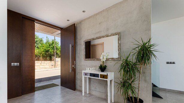 A modern interior with a concrete wall, a wooden door, a white console table with drawers, a mirror, and a potted plant. - YourHouse Casa Llubi,  house with private pool and air conditioning (Llubi)