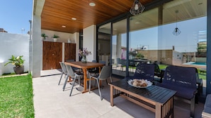 An outdoor patio with a wooden table and chairs, a glass-enclosed dining area, and potted plants. - YourHouse Casa Llubi,  house with private pool and air conditioning (Llubi)