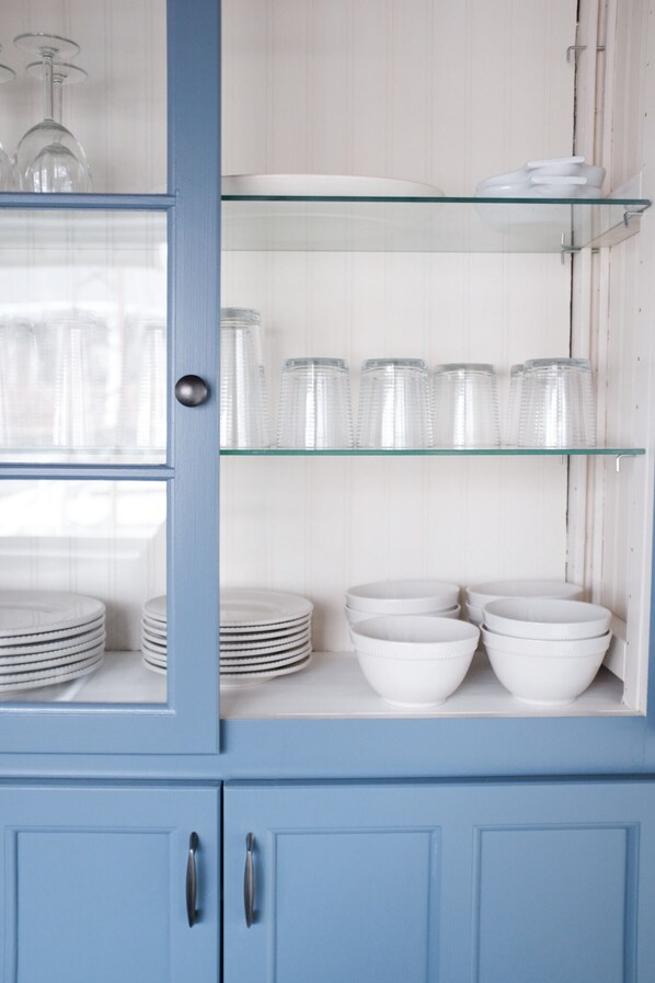 A blue cabinet with glass shelves containing white plates, bowls, and glassware. - Birder's Paradise | 300° of Waterfront Views (Leamington)
