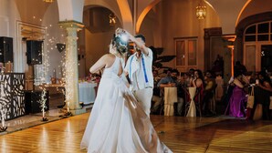 Una recepción de boda en un salón con suelo de madera y techos abovedados.