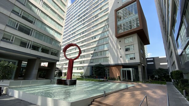 Un edificio moderno con una fuente central y una escultura roja.