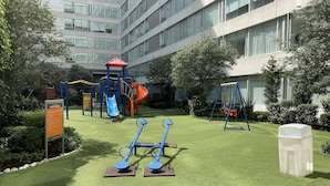 Un parque infantil con tobogán, columpios y equipamiento para hacer ejercicio.