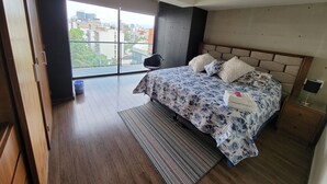 Un dormitorio moderno con una cama grande, vistas a la ciudad y suelo de madera.