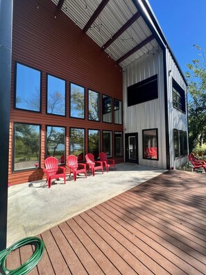 Un bâtiment moderne doté de grandes fenêtres et d’une terrasse avec des chaises rouges.