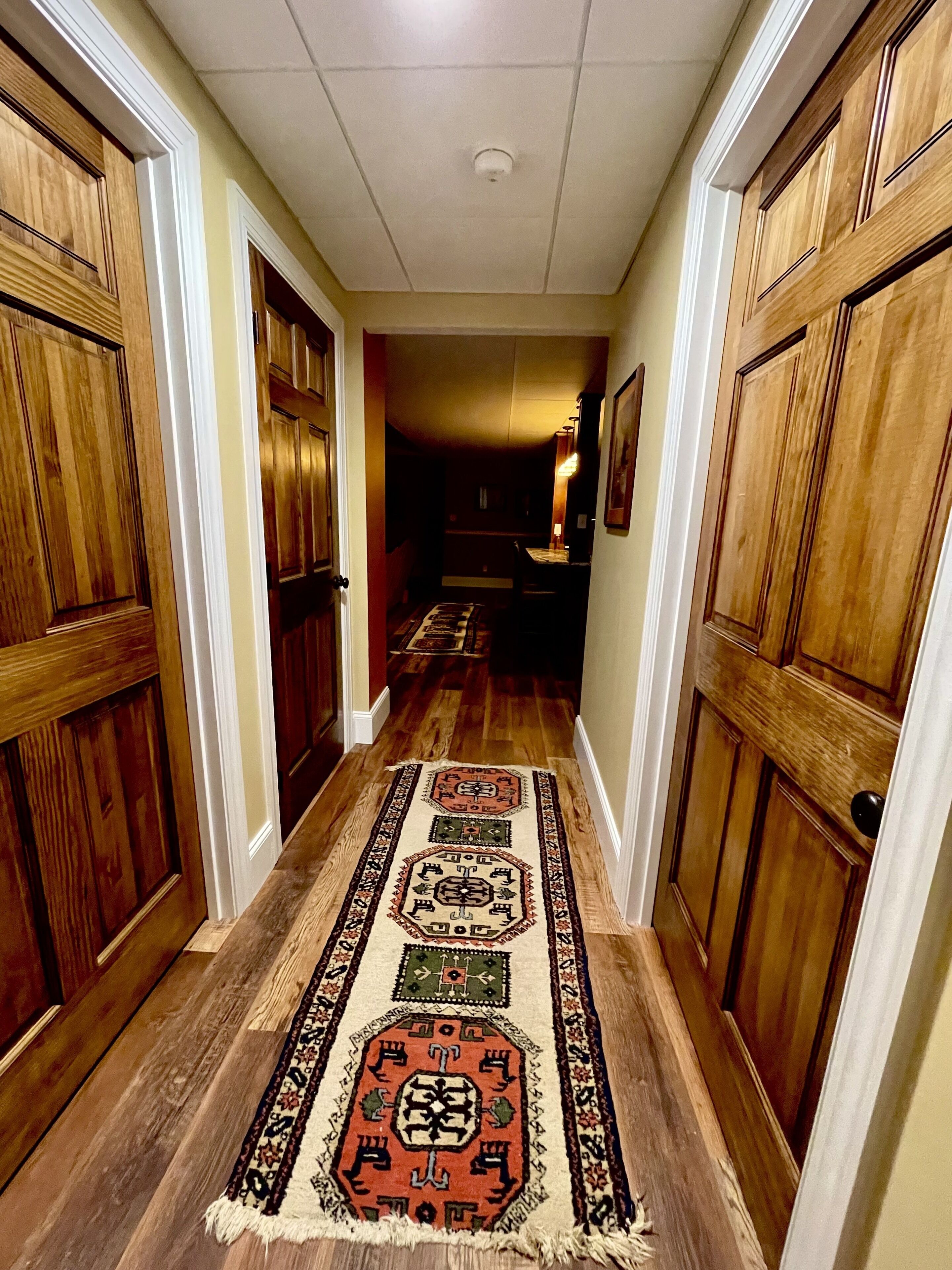 Un couloir avec des portes en bois et un tapis à motifs.