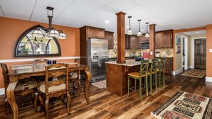 Een ruime keuken met houten kastjes, een centraal kookeiland en een eethoek met een grote tafel en stoelen.