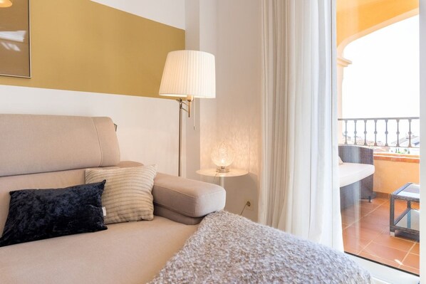 Habitación de hotel con sofá, lámpara y vistas al balcón exterior.