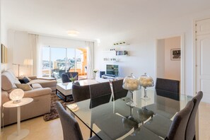 Una sala moderna con una mesa de comedor de vidrio, un sofá y un televisor.