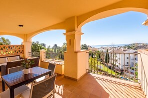 Un balcón con zona de comedor, que incluye una mesa y sillas, y vistas a una zona residencial.
