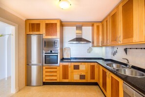 Una cocina moderna con armarios de madera, electrodomésticos de acero inoxidable y una encimera negra.