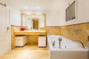 Un baño con un espejo grande, un lavamanos, una bañera y una ducha.
