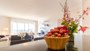 A wooden bowl filled with fruits and flowers on a kitchen counter.