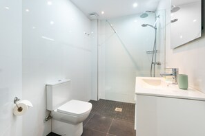 A modern bathroom with a toilet, sink, and shower.
