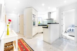 Une cuisine moderne avec des meubles blancs, un îlot central et une vue sur la salle à manger.