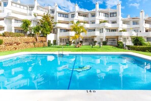 Une piscine dont le fond est marqué du chiffre « 140 », entourée d’un bâtiment blanc doté de balcons et d’un mur en pierre.