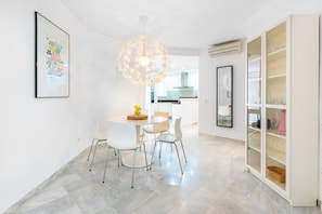 A modern dining area with a round table, white chairs, and a decorative light fixture.