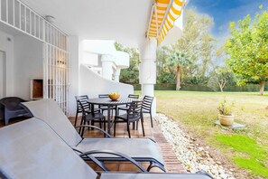 An outdoor patio with a table and chairs, a grill, and a covered seating area.