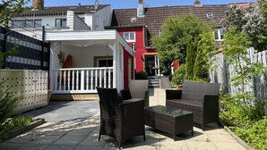 A courtyard with outdoor furniture, a white building with a balcony, and a red house in the background. - Beautiful vacation home directly on the canal (Friedrichstadt)