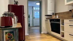 A modern kitchen with a red refrigerator, a coffee maker, and a shelf with kitchen utensils. - Beautiful vacation home directly on the canal (Friedrichstadt)