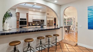 Une cuisine moderne dotée d’un îlot central, de tabourets de bar et donnant sur la salle à manger.
