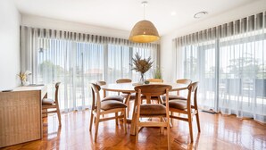 Un comedor moderno con una mesa redonda, seis sillas de madera y una lámpara colgante.