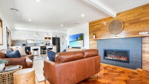 Una sala de estar moderna con un sofá de cuero, una chimenea y una cocina al fondo.
