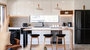 Una cocina moderna con una isla central, dos lámparas colgantes, un horno empotrado y un refrigerador negro.