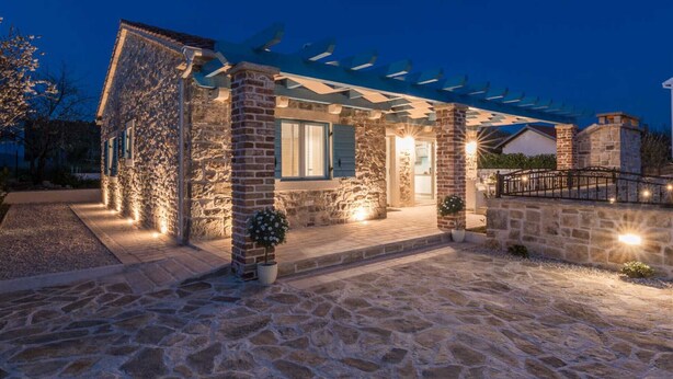 A stone house with a covered porch and outdoor lighting. - Stone Villa Gelosia Rustica with heated pool (Sukošan)