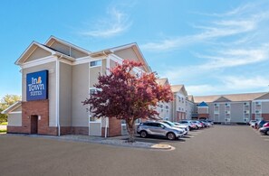 A hotel with a sign reading 'In Town Suites,' a parking lot with several cars, and a tree with red leaves. - Intown Suites Extended Stay Chicago Il - Downers Grove (Downers Grove)