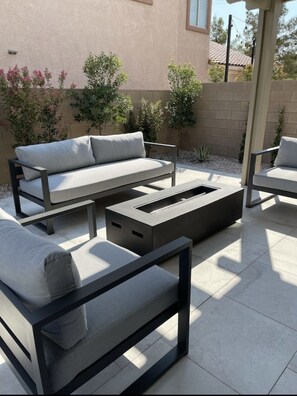 Relax on the patio with a comfortable sofa and armchair, surrounded by lush greenery and a beautiful view.