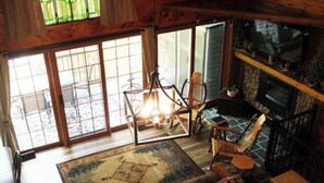 Un salon chaleureux avec une cheminée, une grande fenêtre offrant une belle vue et un tapis à motifs.