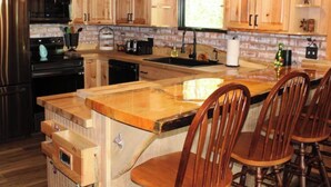 Une cuisine avec des meubles en bois, un réfrigérateur en acier inoxydable, un four à micro-ondes, un évier et un îlot central en bois avec des chaises.