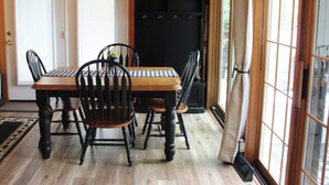 Une table à manger en bois avec des chaises, un buffet noir et une porte avec une pancarte.