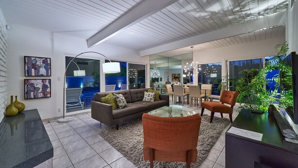 A modern living room with a glass coffee table, a sofa, and a dining area with a glass partition. - NEW!!! The Cosmo. A mid-century gem in the desert (Palm Springs)