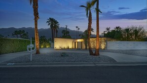 A modern building with a well-maintained garden, palm trees, and a view of distant mountains. - NEW!!! The Cosmo. A mid-century gem in the desert (Palm Springs)