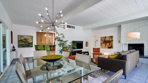 A modern living room with a glass dining table, a sofa, and a fireplace. - NEW!!! The Cosmo. A mid-century gem in the desert (Palm Springs)
